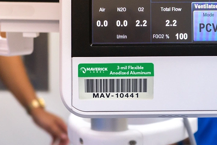 A piece of equipment displaying a green custom asset label with a barcode and identification information.