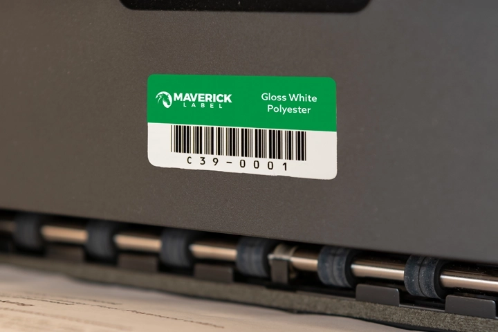 A green asset tag label with a barcode and identification details attached to a piece of equipment.