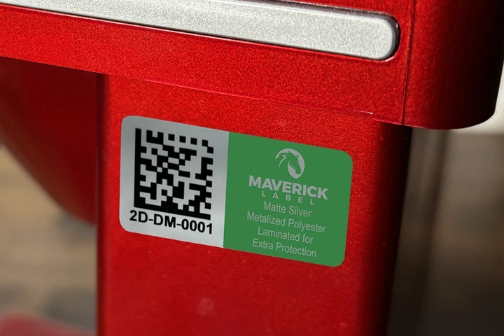 A green custom asset sticker with a QR code and identification details affixed to a red piece of equipment.